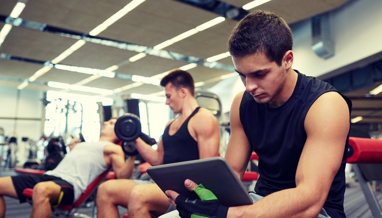 group of men with tablet pc and dumbbells in gym