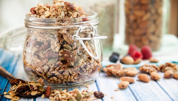 A glass jar in a blue wooden table overfilled with granola