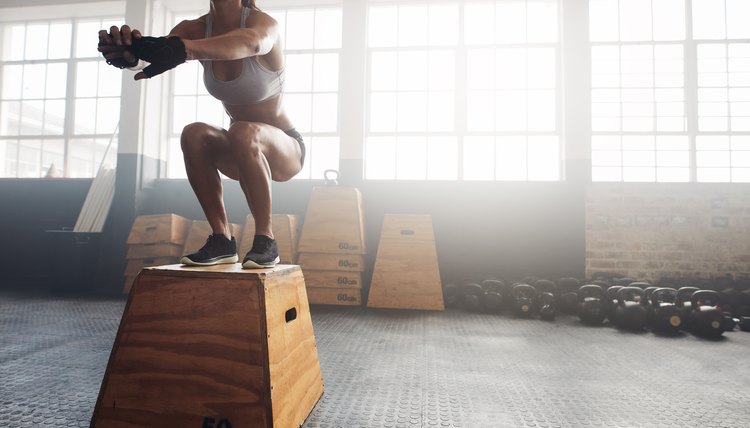 Fitness woman doing box jump workout at gym