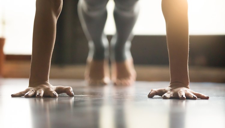 Young yogi woman standing in Plank pose, home interior backgroun