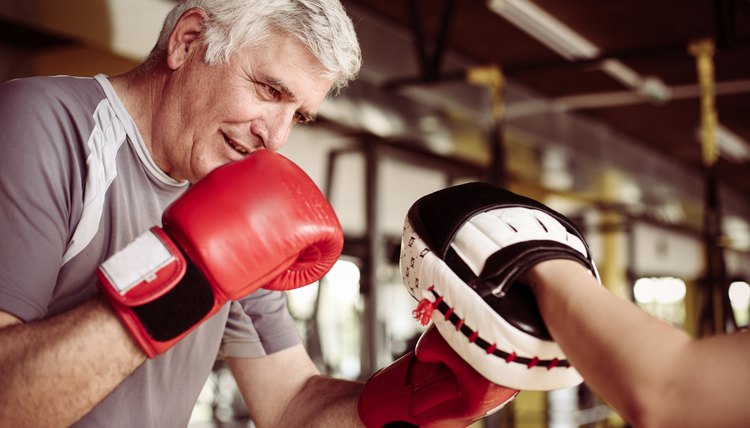 Older man boxing in gym. Senior man with personal trainer.