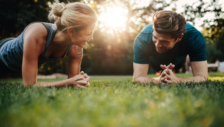 Fit young man and woman exercising in park