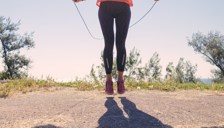 Girl in sportswear and sneakers jumping with a skipping rope