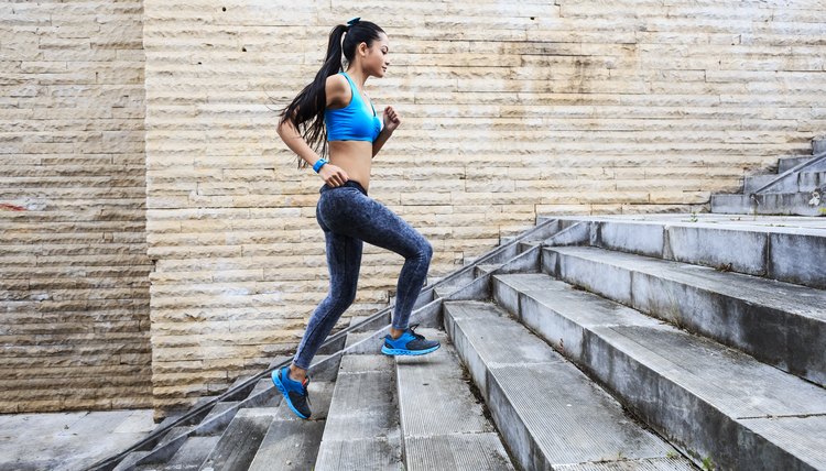 Female runner moving up on stone stairs-side view