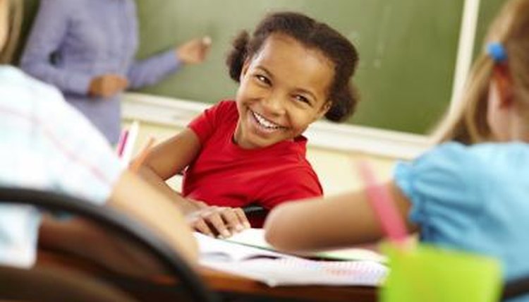 Young girl student talking to other girl students in the classroom.