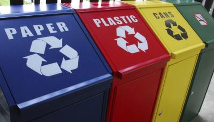 Four colorful recycling bins lined up by category outside.