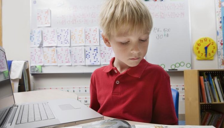 Young boy student reading books and using the internet.