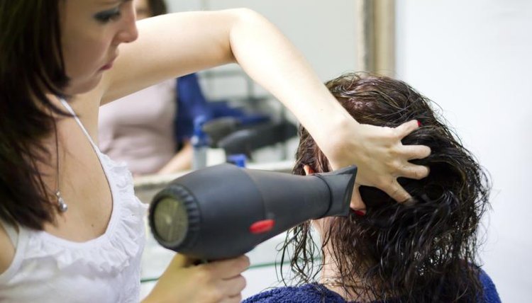 A hairdresser dries a clients hair.