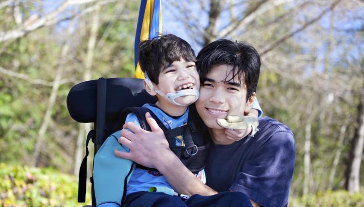 Young boy and his brother sitting in a custom-made wheelchair.