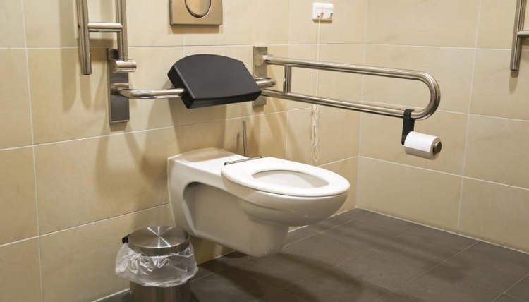 A bathroom with side rails and extended toilet seat.