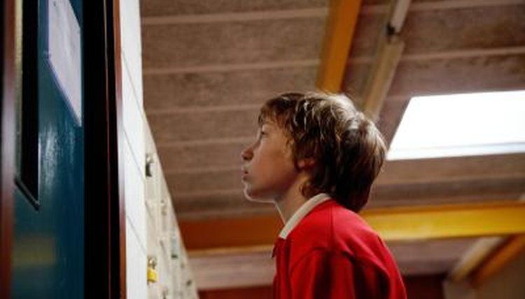 A school boy stands outside of an administrator's office.
