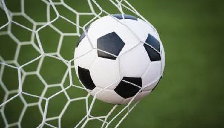 Soccer ball being kicked into goalie net