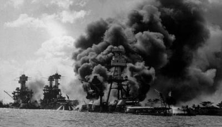 USS Arizona burning in Pearl Harbor during Japanese attack, to the left is the USS Tennessee and USS West Virginia