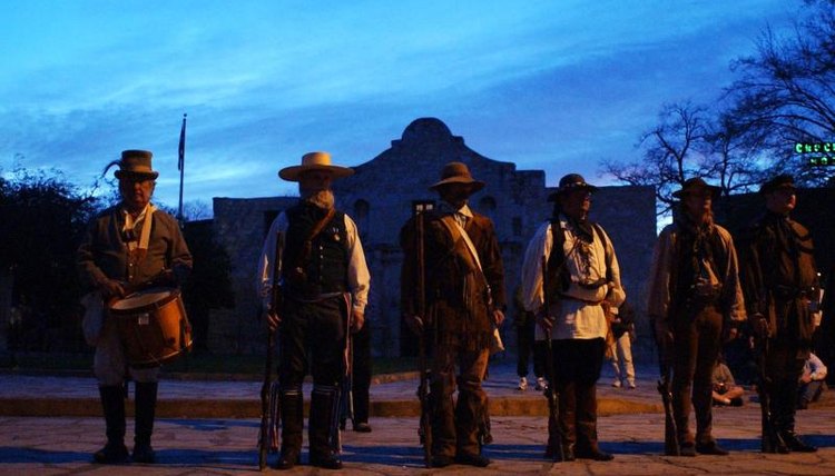 Re-enactors stand in front of the Alamo at dawn
