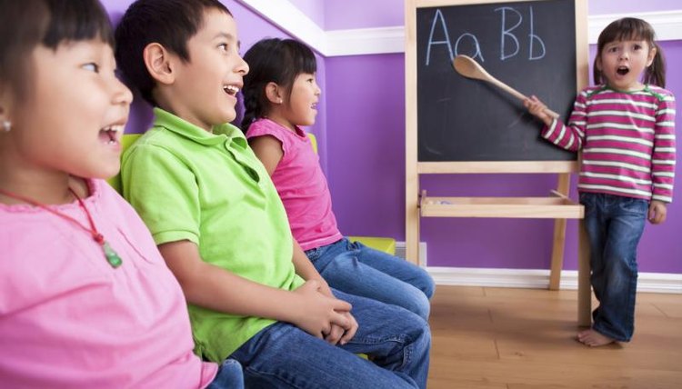 Young child pointing to a chalkboard easel.