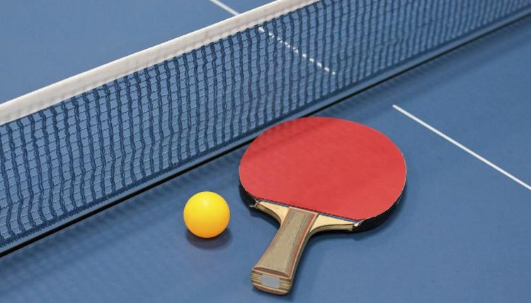 Paddle, ball and net on a ping pong table.