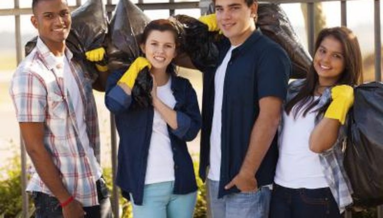 A group of students wearing gloves holding garbage bags.