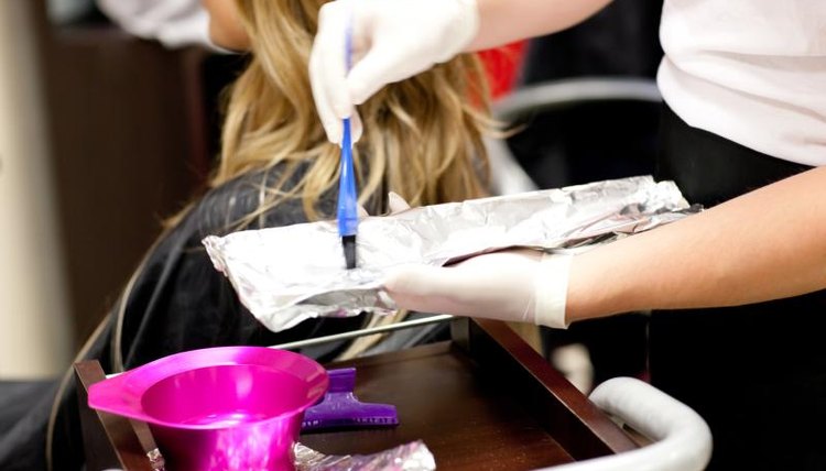 A cosmetologist mixing hair color for a client.