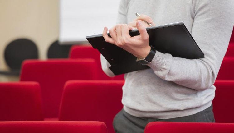 A man filling out a survey in an auditorium.
