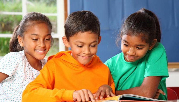 A small group of three children sit and read together