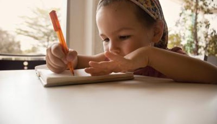 Young girl writing and smiling.