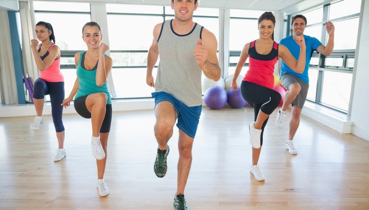 Full length of fitness class and instructor doing pilates exercise