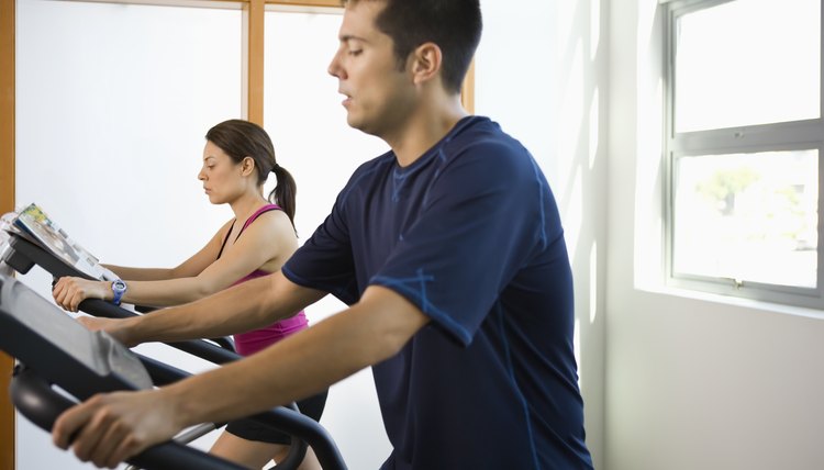 Young couple working out on elliptical machines in gym