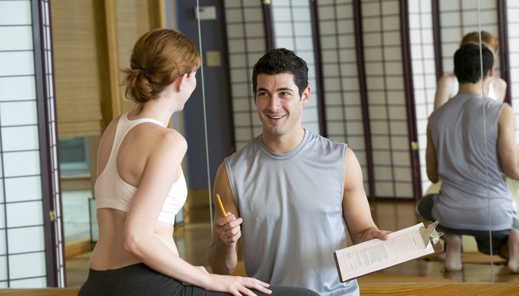 Woman at gym conversing with personal trainer