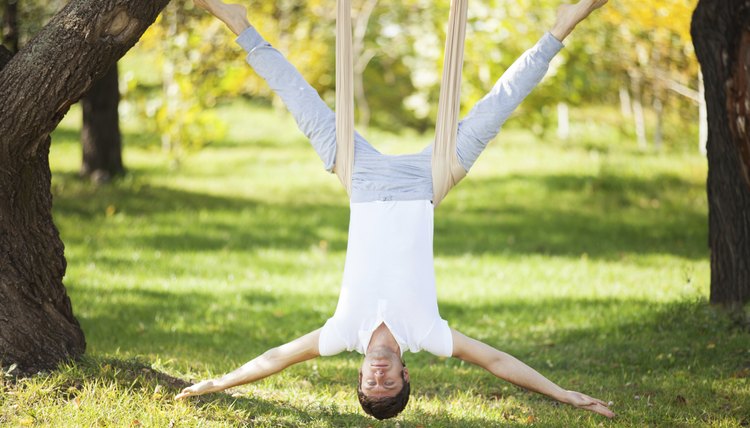 Anti-gravity Yoga, man doing exercises in the park