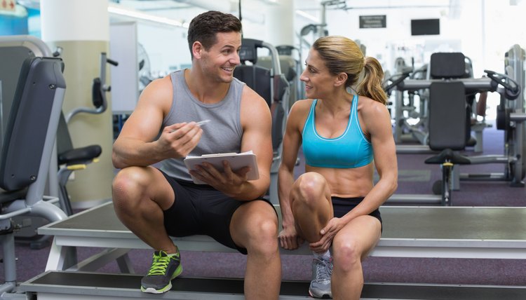 Female bodybuilder sitting with personal trainer talking