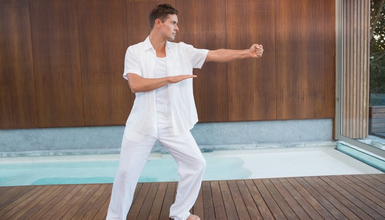 Handsome man in white doing tai chi