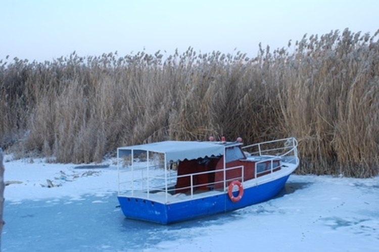 Boat at Frozen Lake image by TekinT from Fotolia.com Fogging a boat's engine is part of the winterization process.