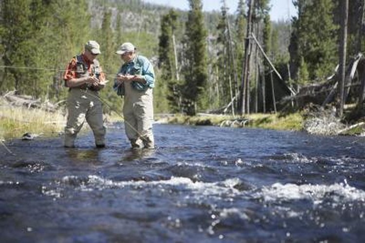 Stewart Sutton/Digital Vision/Getty Images Two men preparing their lines while fly fishing in a river.