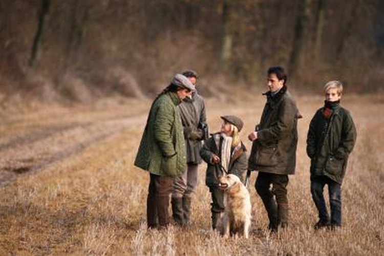 David De Lossy/Digital Vision/Getty Images A group o hunters with a dog in the forest.
