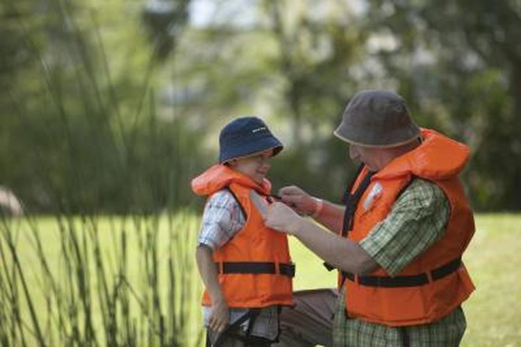 Jochen Sand/Photodisc/Getty Images Grandfather puts a life jacket on his grandson.
