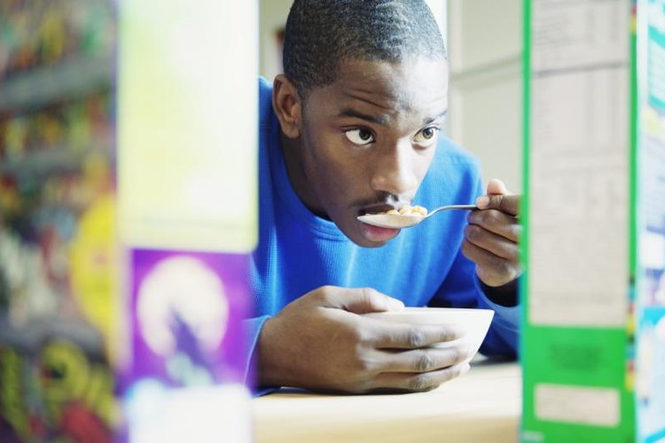 Andersen Ross/Blend Images/Getty Images A man looks at the cereal box while he eats.