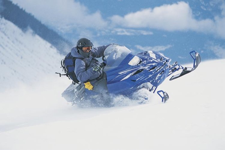 Digital Vision./Photodisc/Getty Images Man turning a fast moving snowmobile.