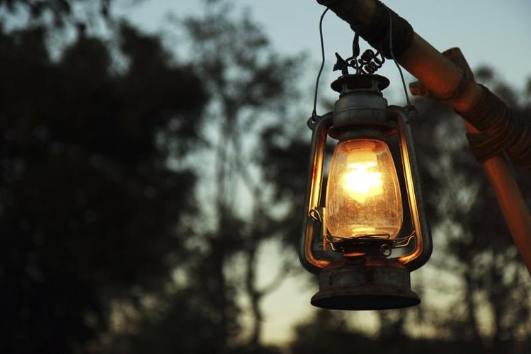 Wittybear/iStock/Getty Images A lantern hanging in fornt of some trees.