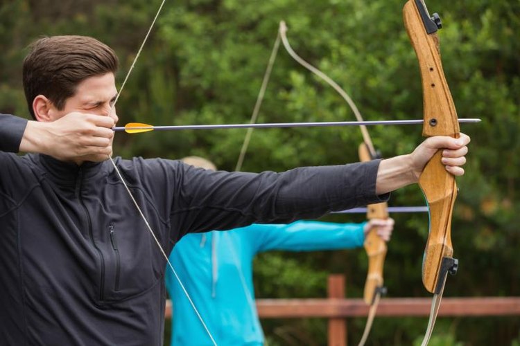 Wavebreakmedia Ltd/Wavebreak Media/Getty Images Man and woman practicing archery outside.