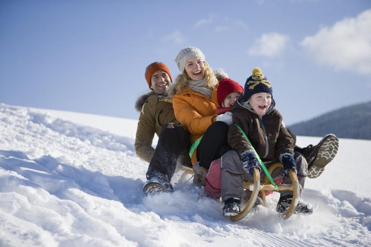 altrendo images/Stockbyte/Getty Images Family riding a toboggan down a snowy hill.
