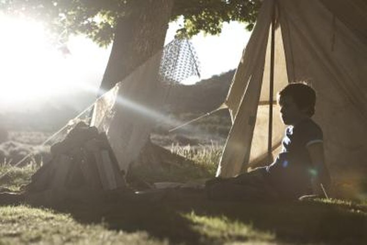 Tay Rees/Photodisc/Getty Images A young boy is sitting by a tent.