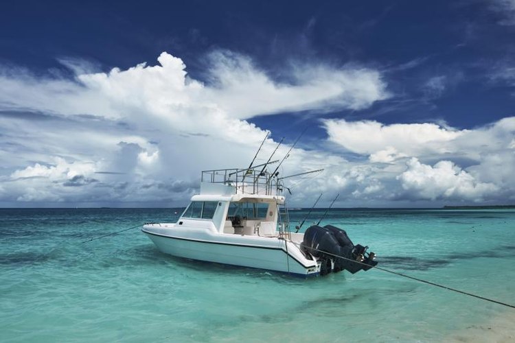 haveseen/iStock/Getty Images A boat with twin motors anchored near shore.