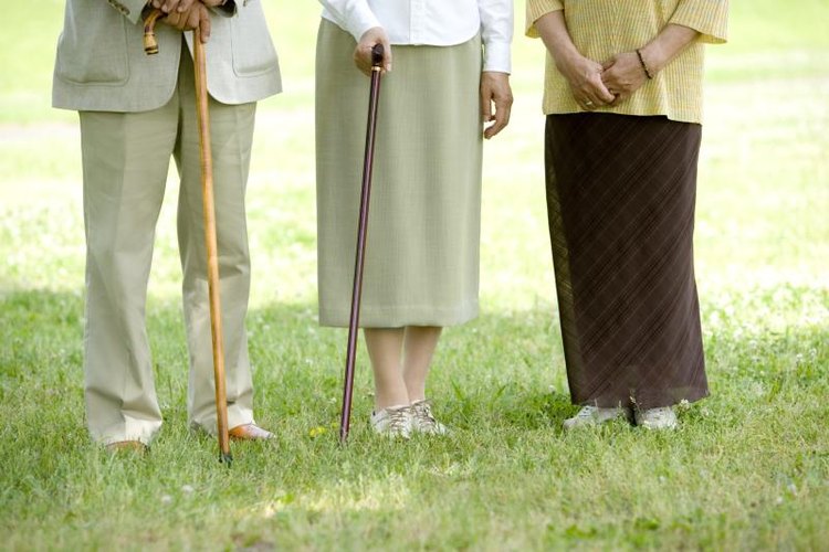 DAJ/amana images/Getty Images Close-up of elderly people holding walking sticks outside.