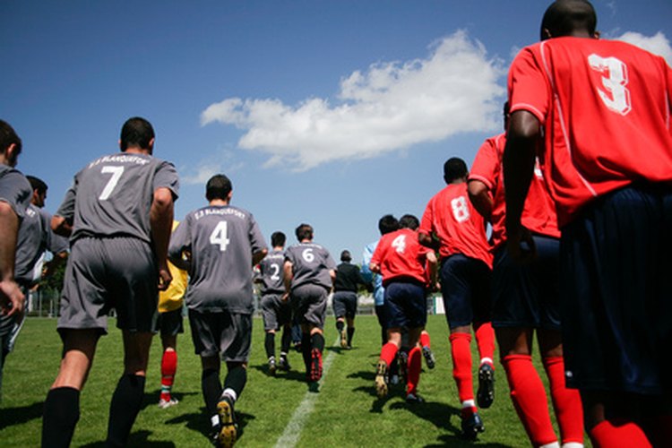 Ambos equipos de fútbol entran al campo antes de lanzar una moneda.