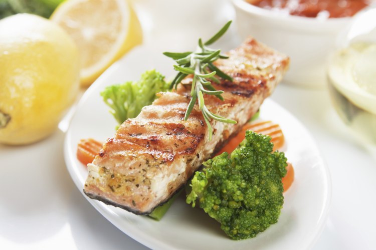 Salmón grillé en un plato con brócoli y zanahorias.
