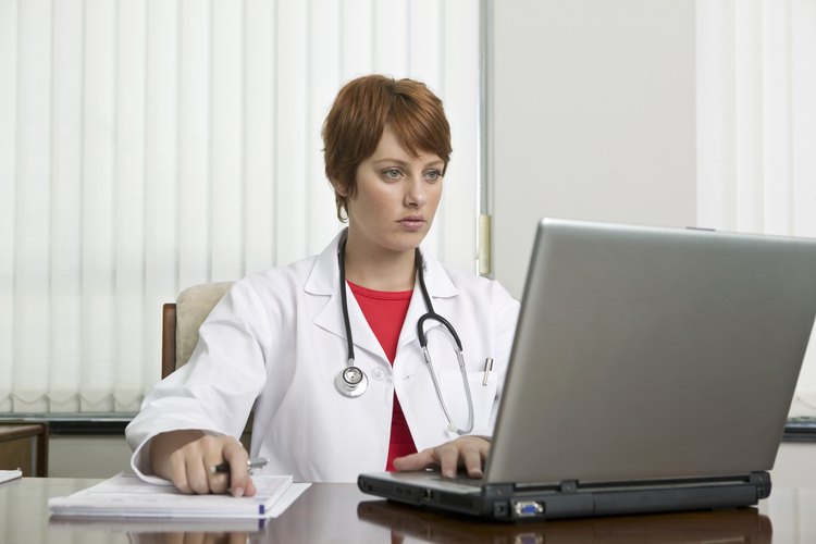 Doctor que mira la computadora portátil.