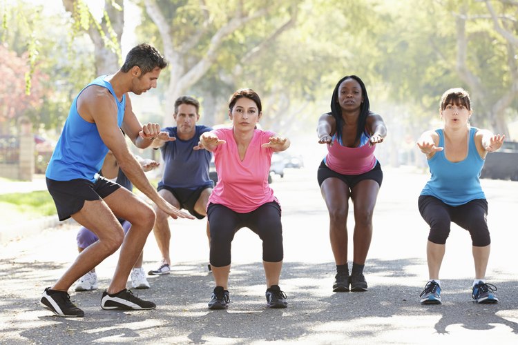 Un grupo de personas ejercitándose al aire libre con un entrenador.