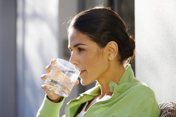 Mujer bebiendo agua fuera de la casa.
