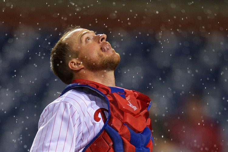 El receptor de los Filis Erik Kratz trata de atrapar una bola alta en la lluvia en un juego de 2013.