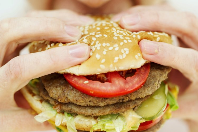 Una mujer comiendo una hamburguesa.